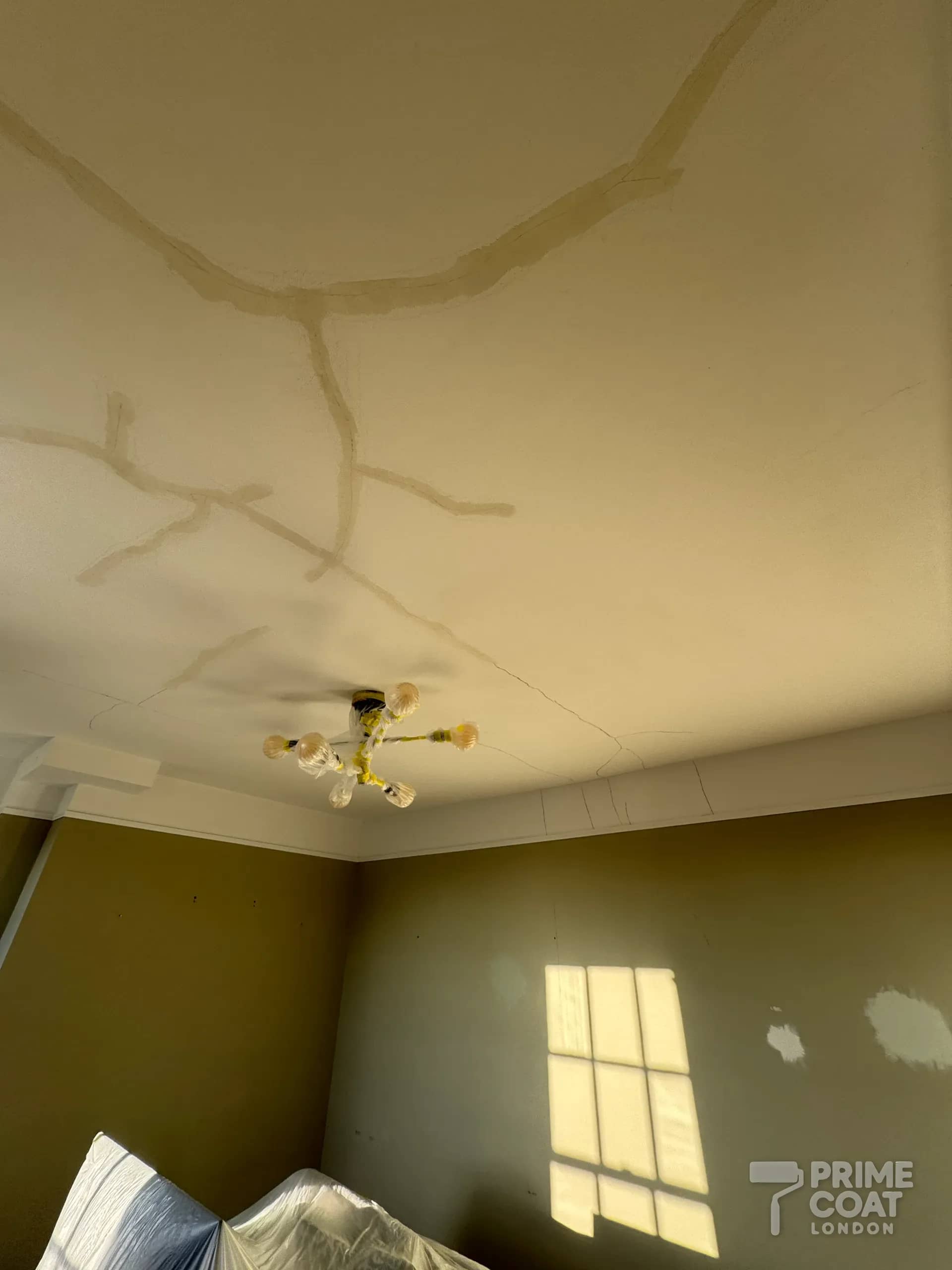 Living-room ceiling in a Battersea SW11 period flat with long cracks filled ready for sanding and repainting