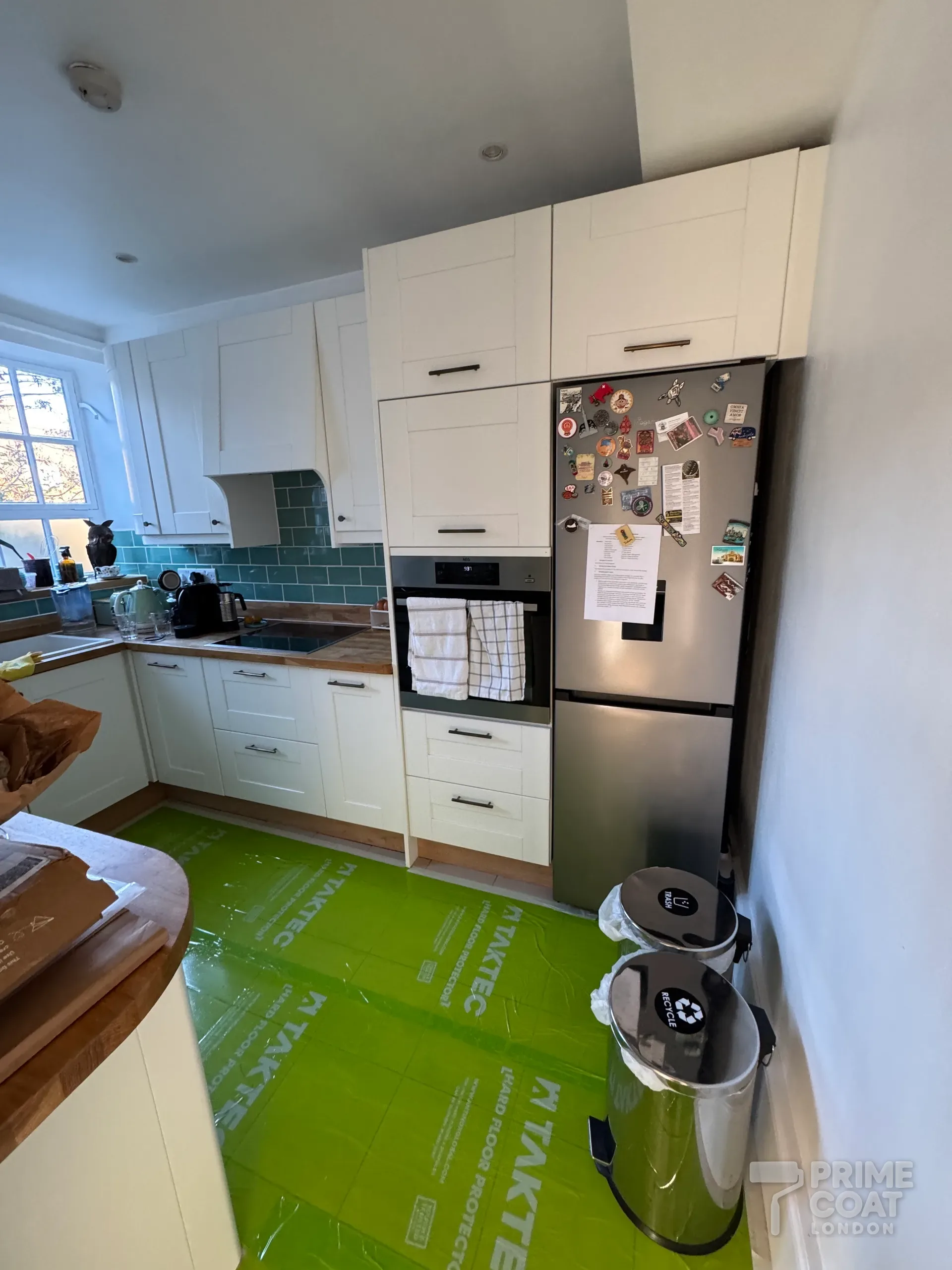 Kitchen in a Battersea SW11 flat ready for painting, the tiled floor covered with hard-floor protection film