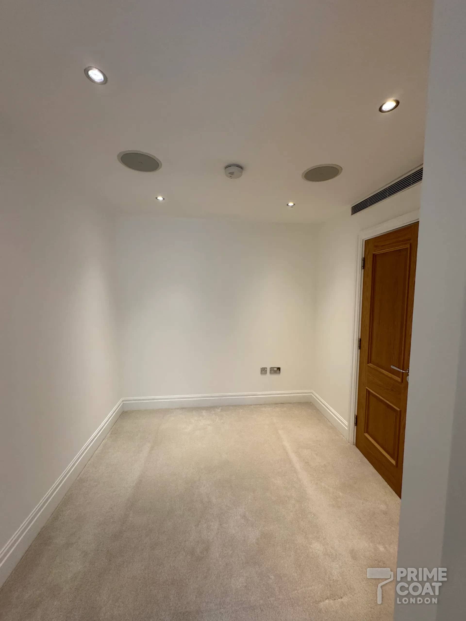 Bedroom in a Chelsea Harbour SW10 apartment after repainting — clean white walls with the original oak door