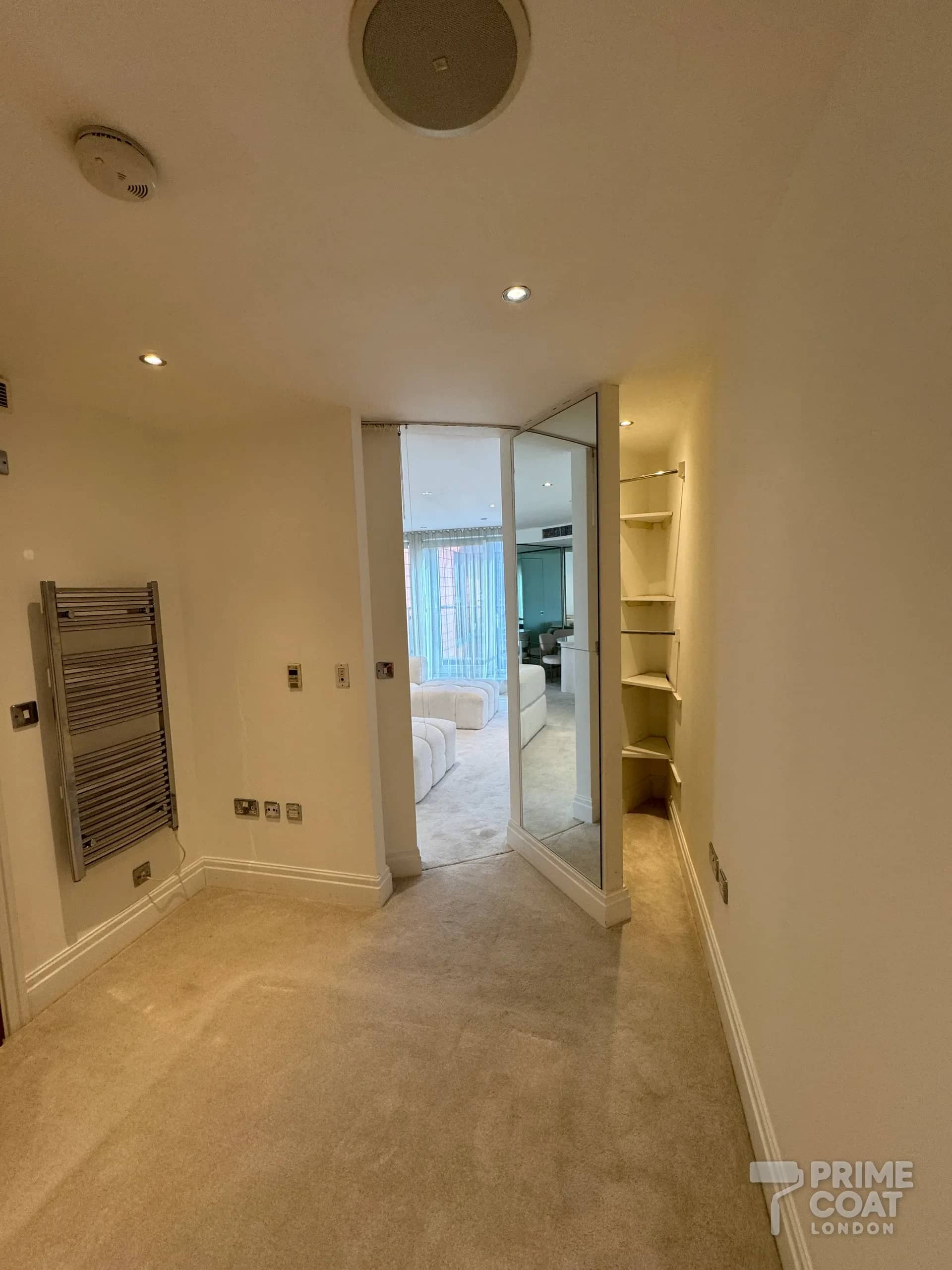 Dressing area off a bedroom in a Chelsea Harbour SW10 apartment after repainting — freshly painted white walls, looking through to the finished living room