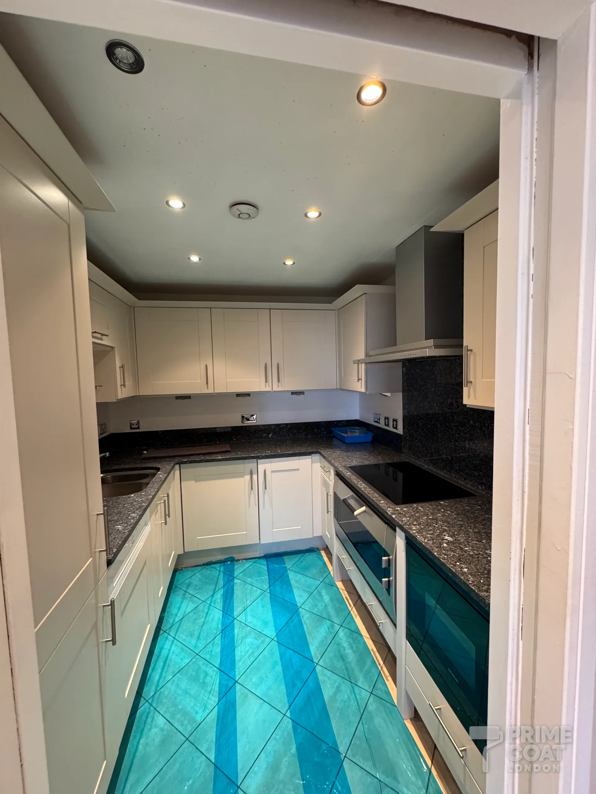 Kitchen in a Chelsea Harbour SW10 apartment ready for painting — tiled floor covered in protection film and the marked ceiling around the downlights before repainting