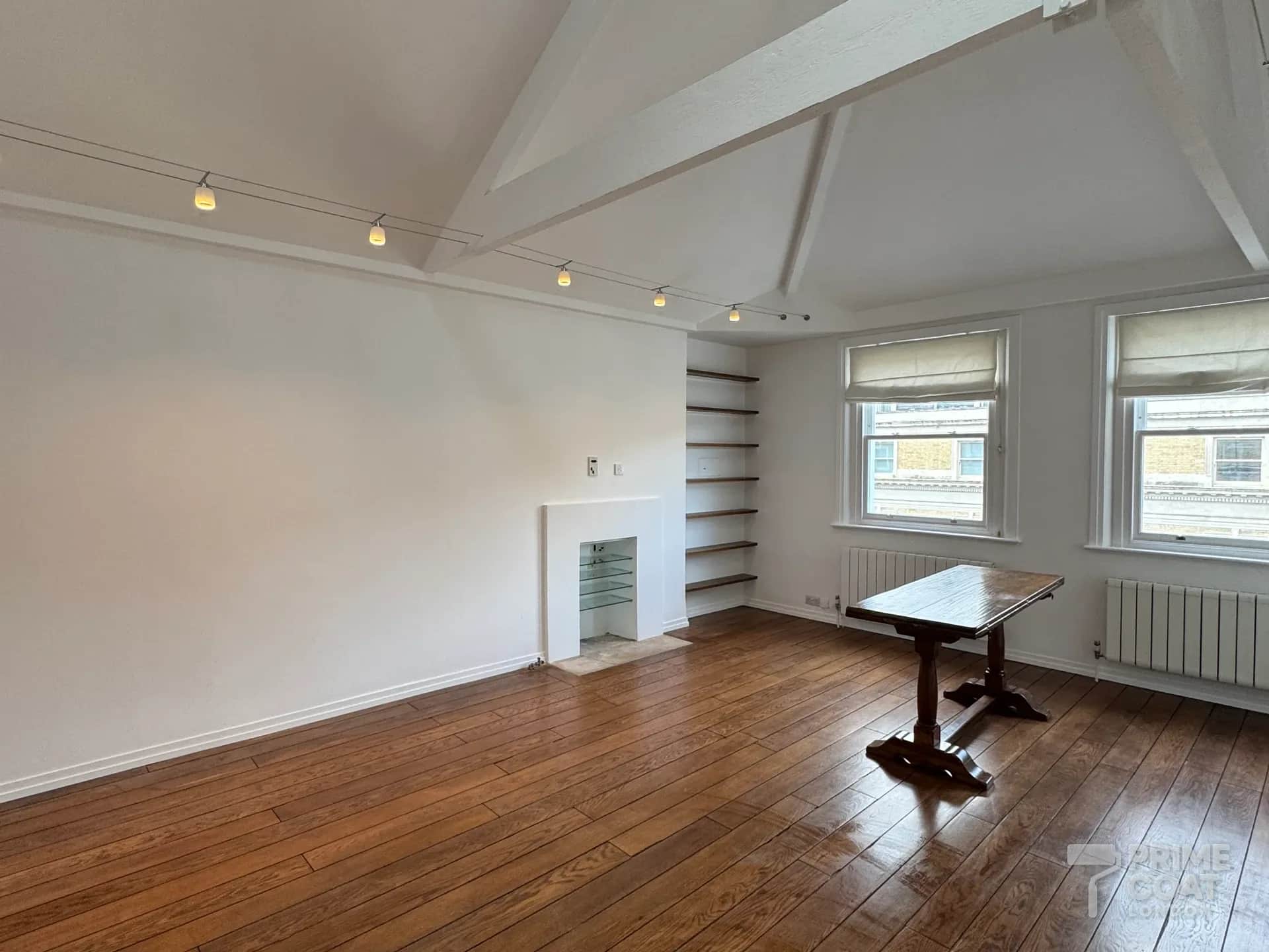 Kensington W8 reception after spray painting — fresh white walls, vaulted ceiling and exposed beams above the oak floor and sash windows