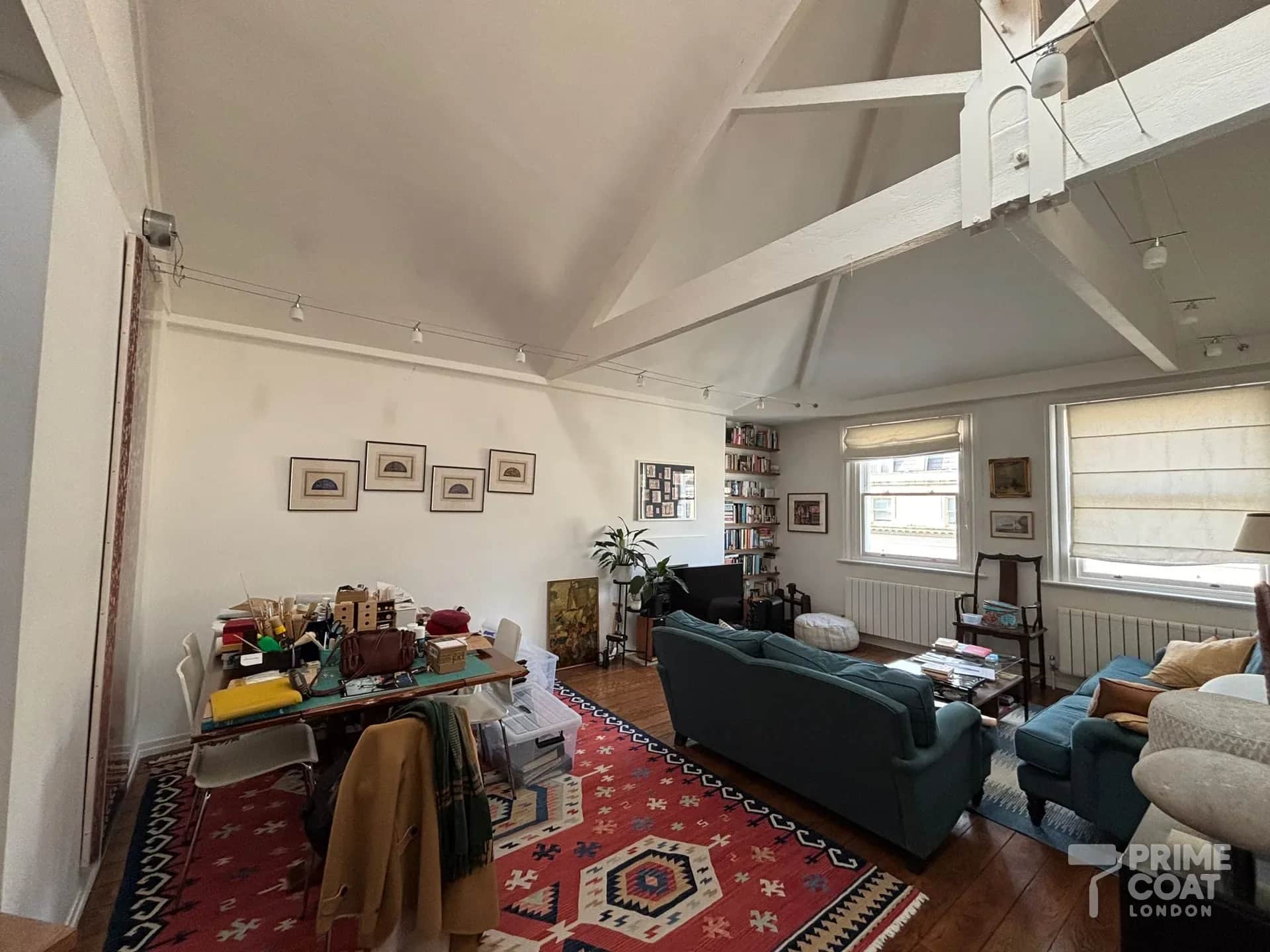 Kensington W8 top-floor reception before repainting — a lived-in room under a pitched ceiling with white beams, marked walls and furniture