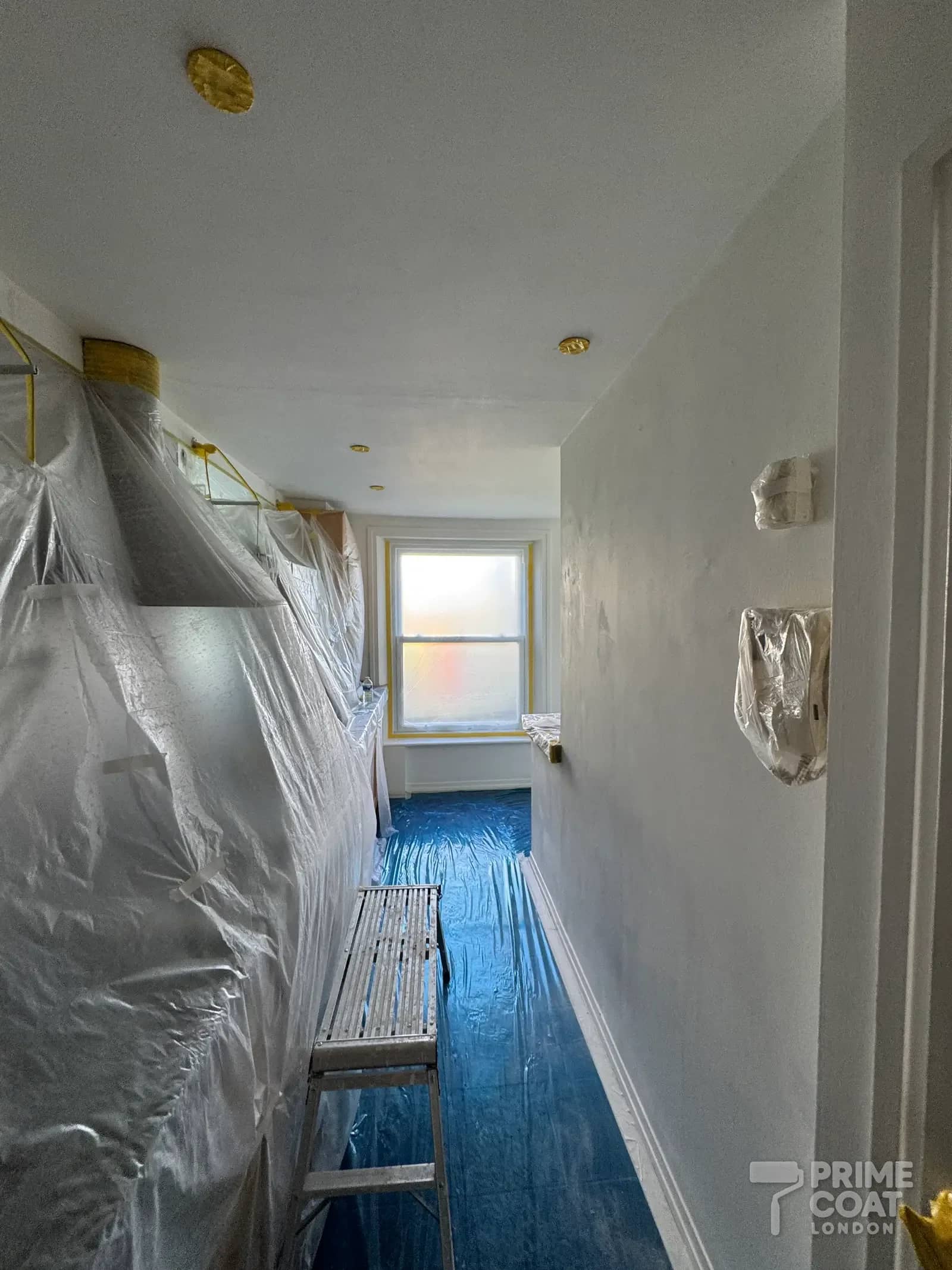 Kitchen in a Kensington W8 flat fully sheeted in plastic and the floor covered before spraying the walls and ceiling