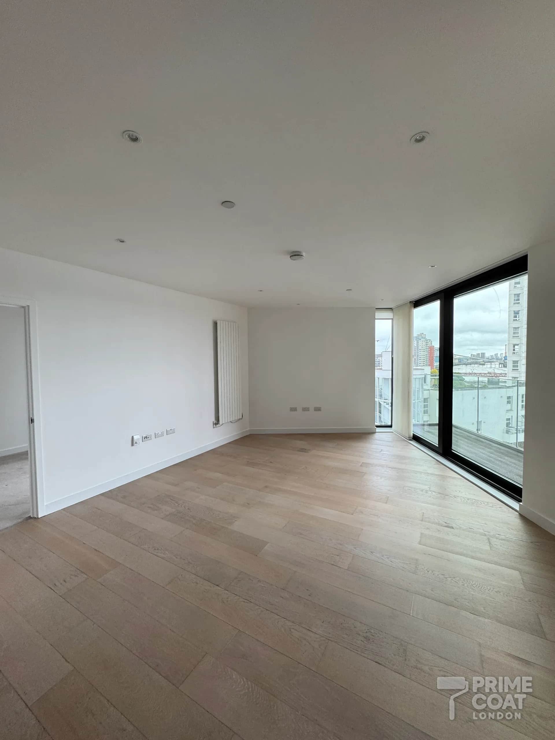 Pontoon Dock E16 living room after repainting — even white walls and ceiling, oak floor uncovered and floor-to-ceiling windows onto the balcony