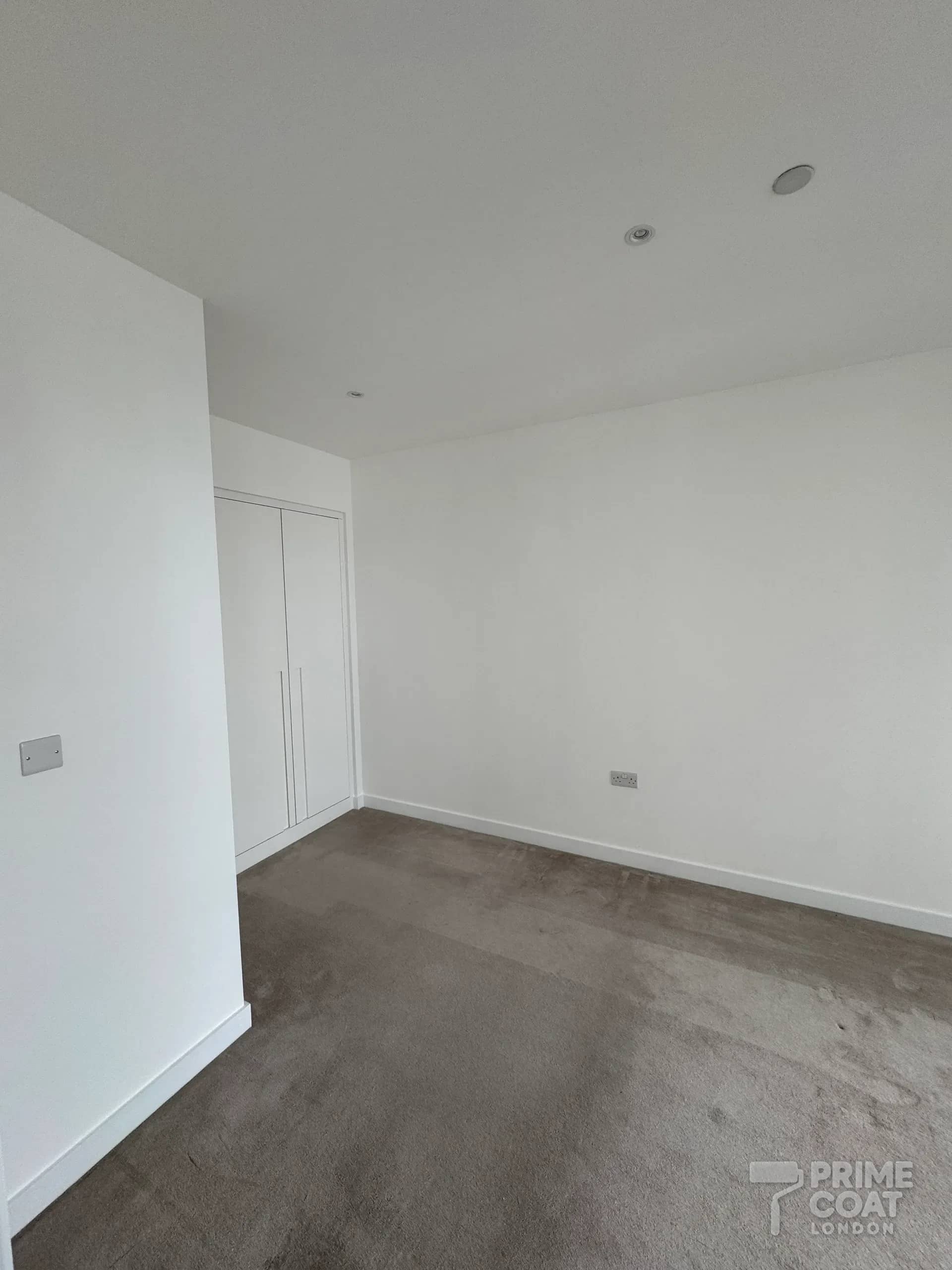 Bedroom in a Pontoon Dock E16 new-build after painting — smooth white walls and ceiling with clean lines along the skirting and around the fitted wardrobe